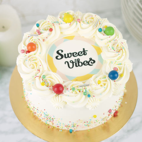 Foto / Logo Taart met de logo van Sweet Vibes erop en gedecoreerd met gekleurde sprinkles.