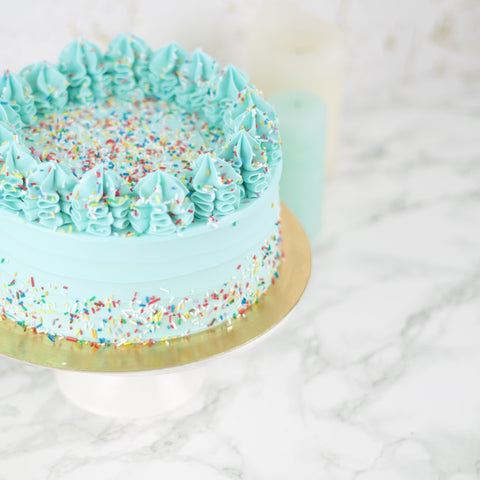 Blauw botercrème taart met toefjes en sprinkles