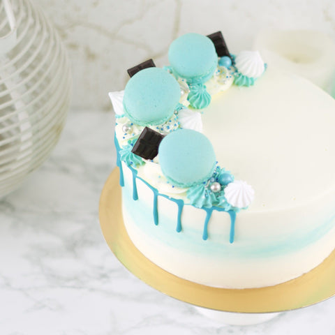 Een feestelijke blauwe taart met heerlijke macarons en chocolade.