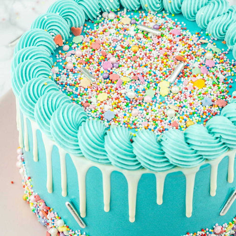 Turquoise-blauwe drip taart met heel veel gekleurde sprinkles