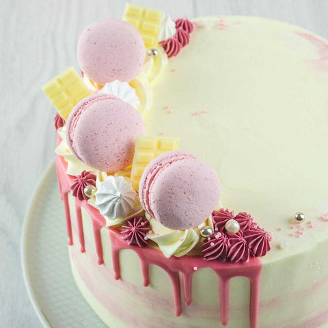 Roze driptaart, versierd met chocolade en macarons